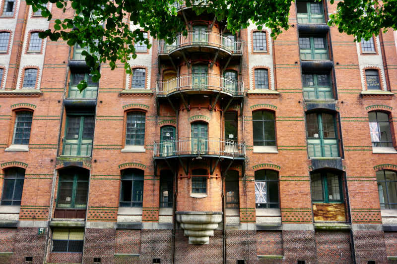 Brick 5-storey apartment building with curved balconies and tall windows.